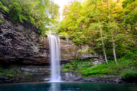 Waterfall cascading into a clear pool surrounded by lush green forest in soft morning light. Fine art landscape photograph by Richard Horst.
