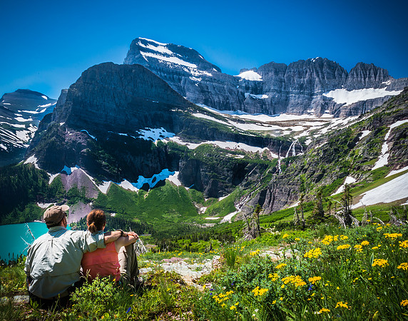 hikers resting among wildflowers overlooking glacier national park mountains landscape by Richard Horst Photography